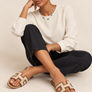Model wearing cream and tan woven cutout slides